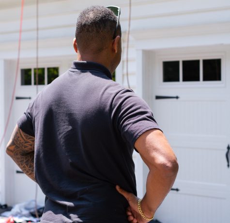 After Heavy Weather Exterior Checklist: Homeowner performing a safe ground-level inspection of a home's exterior after a severe storm.